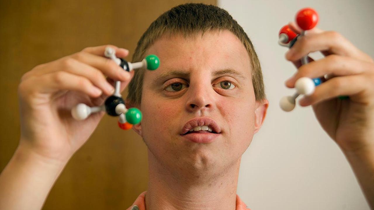 Scientist holding molecular models demonstrating chemistry concepts